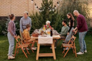 Image of a family gathering around a dining table outside